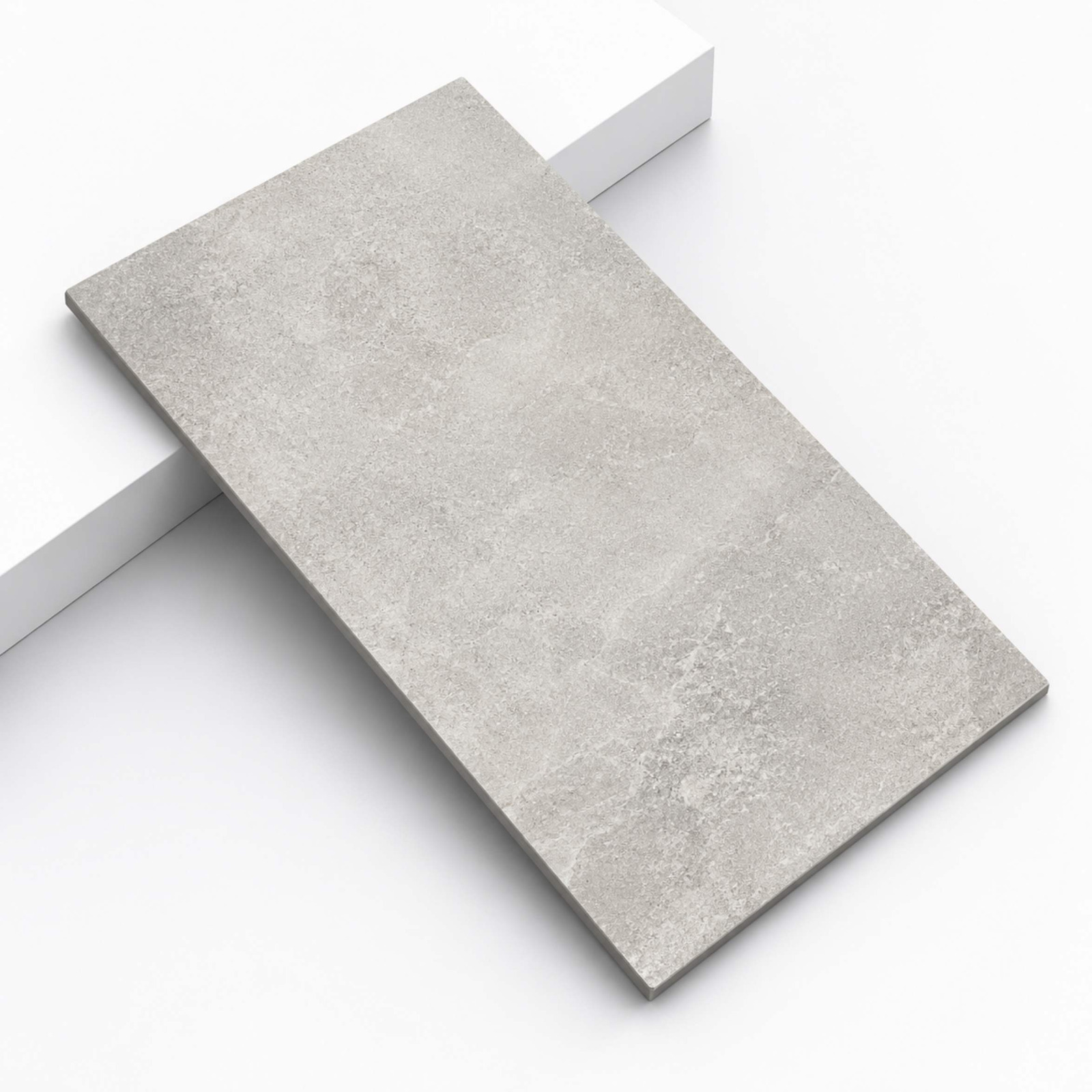 A rectangular light grey cement-look tile slab placed diagonally on a white platform step from alwakil.ae