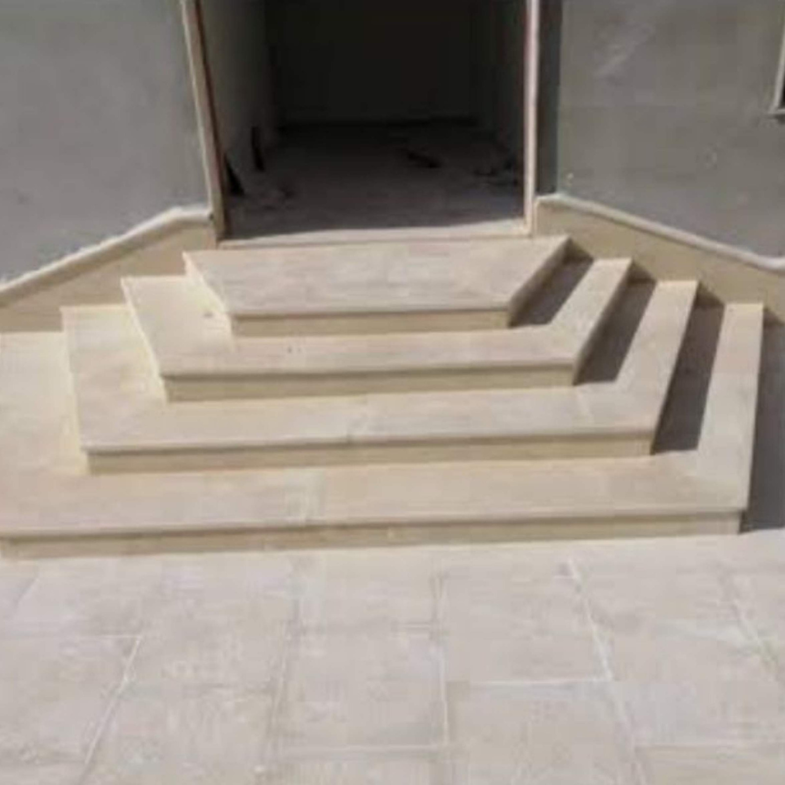 A wide exterior entry staircase showcasing multi-tiered geometric steps crafted from warm beige limestone stone from alwakil.ae